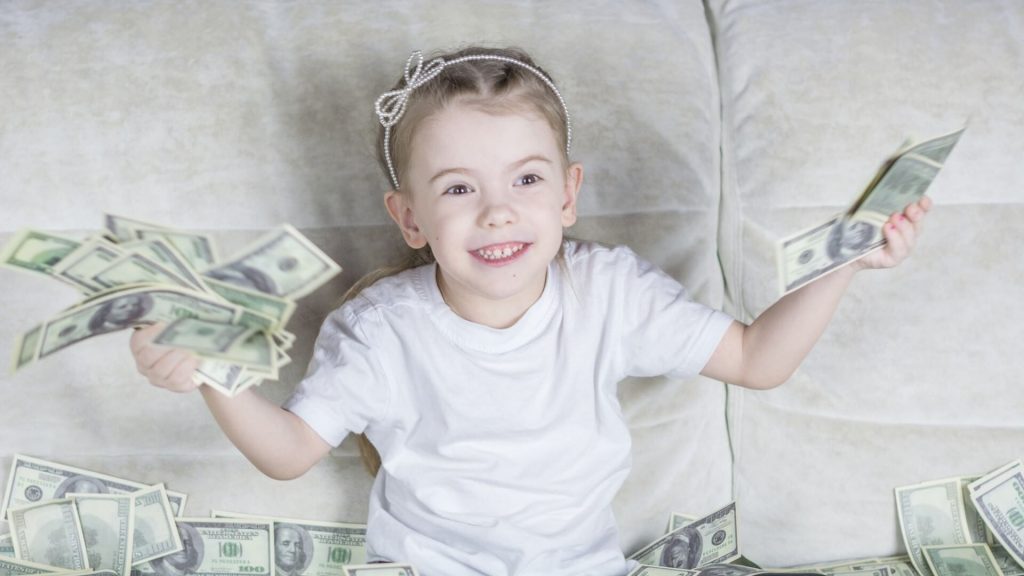 A child surrounded by coins or bills, representing a financial concept or idea.